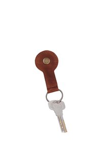 Silver Yale key attached to a round brown leather keychain with a brass button on a white background.