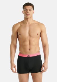 Czarne bokserki z różową elastyczną gumką w pasie ozdobioną logo. Tkanina wydaje się gładka i elastyczna. Krój dopasowany do sylwetki.