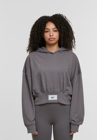 Przycięta szara bluza z kapturem, wykonana z miękkiego materiału, z dużymi rękawami i ściągaczem w talii, ozdobiona naszywką z logo.