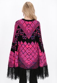Poncho tricotat roz și negru, cu modele geometrice și detalii de franjuri la tiv. Textură moale, cu o silueta confortabilă și supradimensionată.