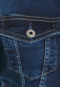 Mörkblå denimjeans med en framficka med bronsstickning och en metallknapp med "Pepe Jeans London" präglat.