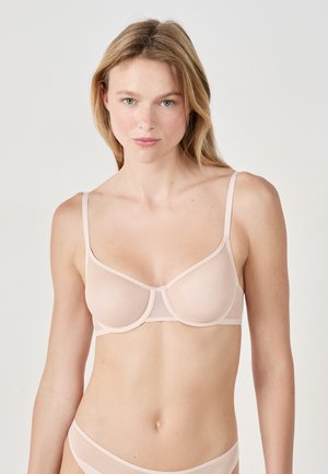 Soutien-gorge rose clair avec des panneaux en tulle transparent, soutien-gorge à armatures, bretelles réglables et finition lisse. Design simple avec des accents matériels minimaux.