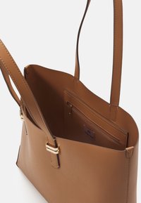 Borsa a spalla in finta pelle color tan, dotata di due manici superiori, un ampio scomparto interno e una tasca interna con zip e un'etichetta del marchio.
