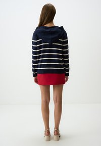 Felpa a righe blu navy e bianca con fondo rosso, dotata di cappuccio con stringa e maniche lunghe, realizzata in un morbido tessuto lavorato a maglia.