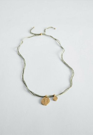 Delicate green cord necklace with adjustable knot and two round gold pendants of different sizes on a white background.