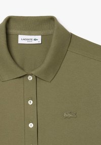 Olivgrön polo skjorta i texturerad tyg, med klassisk krage, treknäppnings plått och broderad logotyp på bröstet.