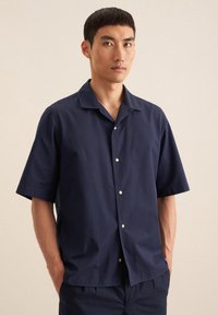 Marineblauwe shirt met korte mouwen in lichte stof, met een klassieke kampkraag en witte knopen, met een ontspannen pasvorm en een soepele textuur.