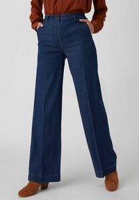 Pantaloni in denim blu scuro a gamba larga con vita alta e tasche frontali, caratterizzati da un design pulito e dettagli di cucitura discreti.