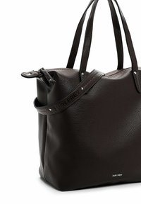 Ruda odinė rankinė su tekstūruotu paviršiumi, dviem rankenomis, metalinėmis detalėmis ir šiek tiek išplečiama viršuje; šone įspaustas logotipas.