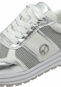Vit sneaker med silverdetaljer, meshnät och gummisula. Snörad design med en cirkulär logotyp på sidan.
