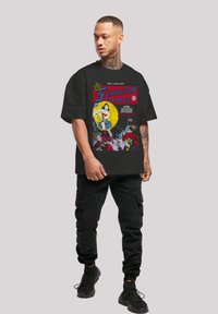 Black graphic t-shirt featuring "Sensation Comics" print with a colorful comic design. Material appears cotton, structured short sleeves and loose fit.