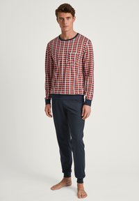 Herren Pyjama-Set mit einem rot-blau karierten Langarmhemd mit Tasche und marineblauen, schmal geschnittenen Hosen mit gerippten Bündchen.