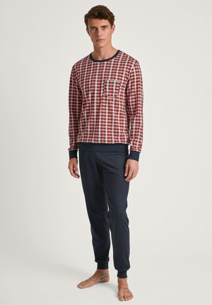 Ensemble de pyjama pour homme comprenant une chemise à manches longues à carreaux rouges et bleus avec une poche et un pantalon ajusté bleu marine avec des poignets côtelés.