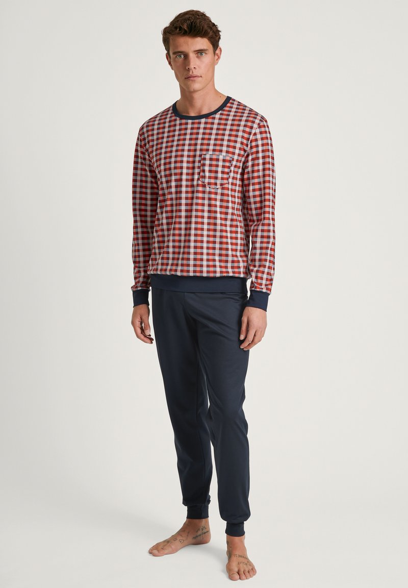Herren Pyjama-Set mit einem rot-blau karierten Langarmhemd mit Tasche und marineblauen, schmal geschnittenen Hosen mit gerippten Bündchen.
