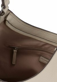 Borsa a mano in pelle beige chiaro con superficie texturizzata, dotata di una tasca interna con zip e foderata con un interno liscio.