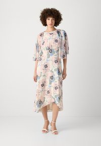 Floral midi dress in soft pink, featuring flowing sleeves, a relaxed waist, and a high-low hem. Fabric has a smooth, lightweight texture.
