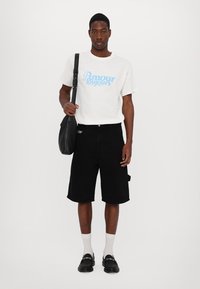 White t-shirt with blue "Amour Toujours" text, black shorts, black shoulder bag, white socks, black slip-on shoes. Simple design and fit.