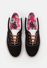 Czarne tenisówki z płótna z białymi akcentami, brązowymi sznurowadłami i kolorowym kwiatowym wzorem na wkładce. Biała gumowa podeszwa z detalem szwu.