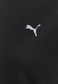 Camiseta deportiva negra con tejido texturizado y canales verticales, y un logotipo de Puma en blanco en el pecho.