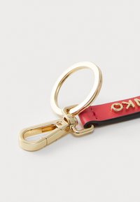 Keychain featuring a gold-toned metal clasp and ring, attached to a red leather strip with embossed lettering and black edge detailing.