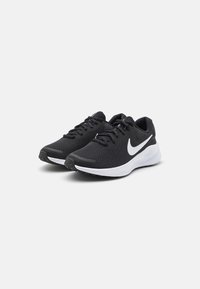Scarpe da ginnastica nere con tomaia in rete testurizzata, suola intermedia bianca e logo Swoosh nero prominente. Presentano lacci e una suola imbottita.