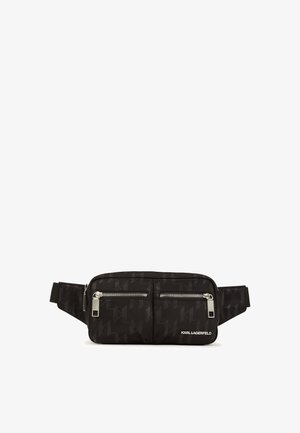 Črni tkaninski pas, ki ima teksturiran vzorček, dva sprednja žepka z zadrgo, srebrne kovinske detajle in nastavljiv trak. Logotip na sprednji strani.