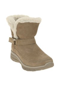 Tan suède laars met een faux fur voering, korte schacht en een banddetail met een metalen gesp. Rubberen buitenzool voor grip.