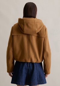 Bruine wolblend hoodie met een ontspannen pasvorm, voorzien van gestikte details en een gladde textuur, gecombineerd met een donkerdenim rok.