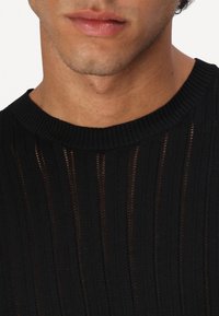 Maglione nero a maglia con texture a coste e scollatura a girocollo, impreziosito da righe verticali per un tocco di design in più.