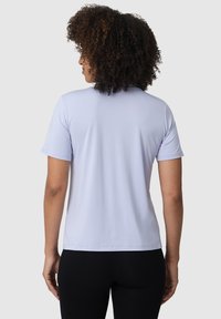 Světle fialové tričko s krátkým rukávem vyrobené z hladké tkaniny, s kulatým výstřihem a volným střihem, kombinované s černými legínami.