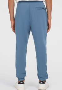 Light blue jogger pants with elastic waistband, tapered legs, and a single back pocket. Fabric appears soft and textured.