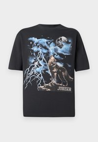Juoda marškinėliai su vilko grafika mėlynais ir sidabriniais tonais, žaibo motyvu ir žodžiu „JORDAN“ apačioje. Trumpomis rankovėmis, įprasto silueto.
