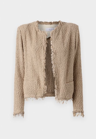 Veste beige texturée avec une silhouette courte, des bords bruts, une ouverture à l'avant et deux poches, confectionnée dans un matériau tissé et duveteux.