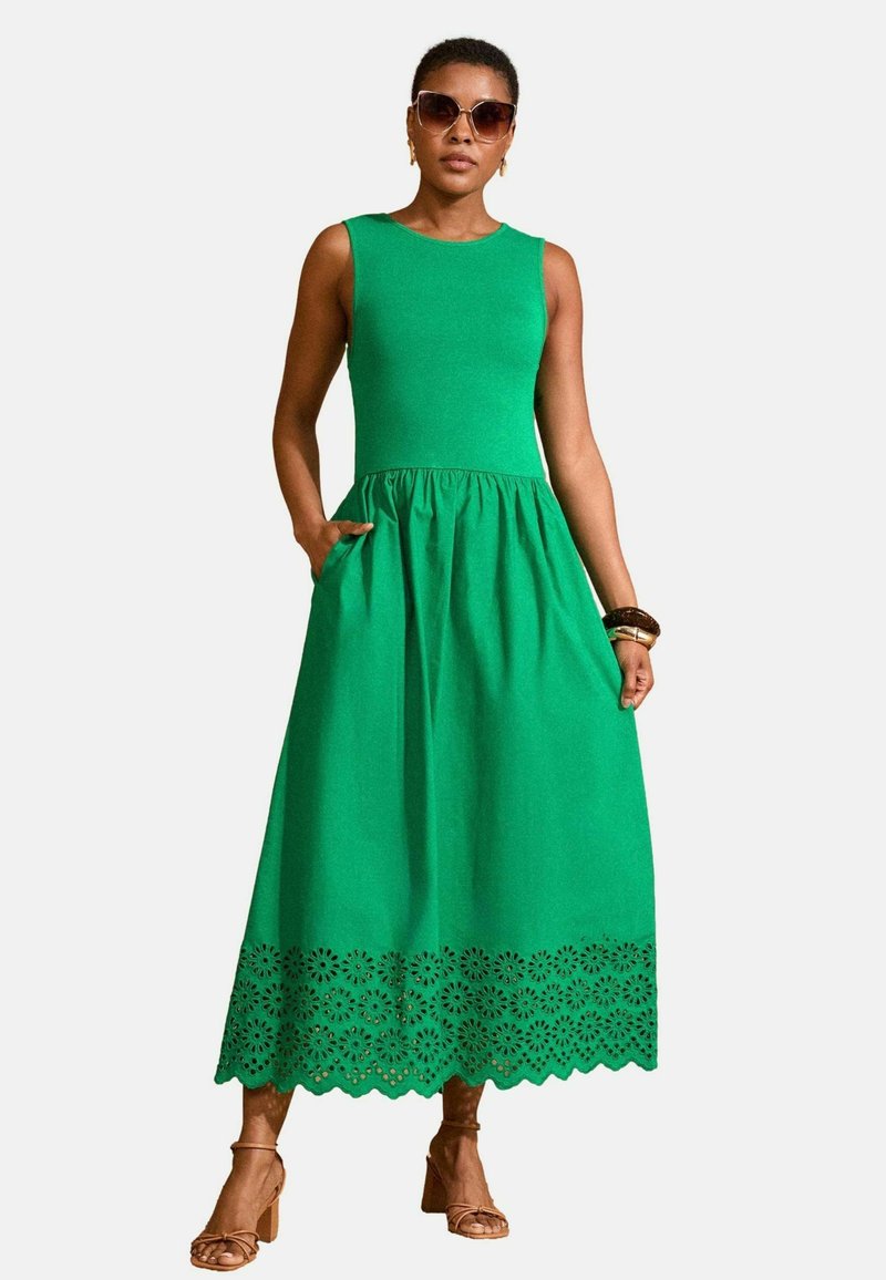 Vihreä ilmanhiha maxi-mekko puuvillasta, jossa on muotoiltu yläosa ja kerätty vyötärö. Koristeellinen laserleikattu kukkakuosi helmassa.