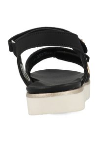 Zwarte sandaal met een platte witte zool en metallic gouden accenten. Beschikt over verstelbare banden en een gladde, getextureerde voetbed.