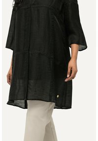 Tunic nera semi-trasparente con vestibilità comoda, maniche a tre quarti, design a patchwork e un piccolo dettaglio dorato sull'orlo.