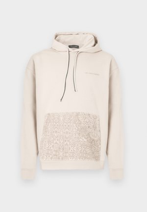 Beige katoenen hoodie met een gestructureerd patroonontwerp op de onderste helft, zwarte trekkoorden en subtiele branding op de borst.
