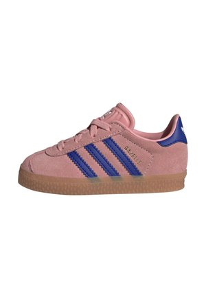 Różowy zamszowy sneaker Adidas Gazelle z niebieskimi paskami i zakładką na pięcie, posiada gumową podeszwę i wiązanie na sznurówki, widoczne logo z boku.