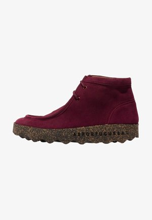 Niedriger bordeauxfarbener Wildlederschuh am Knöchel mit zwei Ösen und dicker brauner gesprenkelter Sohle mit geriffeltem Boden und Markennamen an der Seite.