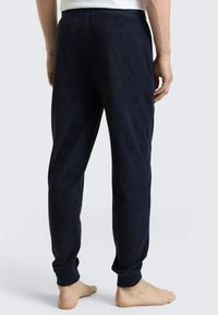 Pantalons de survêtement en polaire bleu marine avec une taille élastique, des jambes fuselées et des poignets côtelés. Texture douce, conçue pour le confort et la chaleur.