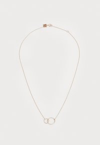 Collar en tono dorado con una cadena ajustable, dos círculos entrelazados y un cierre con una pequeña etiqueta. Textura suave y diseño minimalista.