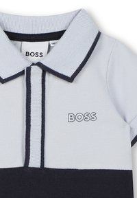 Polo shirt bleu clair avec des accents marine, présentant un col replié et un logo "BOSS" brodé sur la poitrine avec un fil marine assorti.
