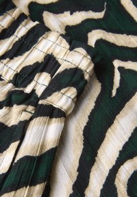 Textured fabric in earthy tones with a green and black abstract pattern. Features elastic gathering detail for flexibility.
