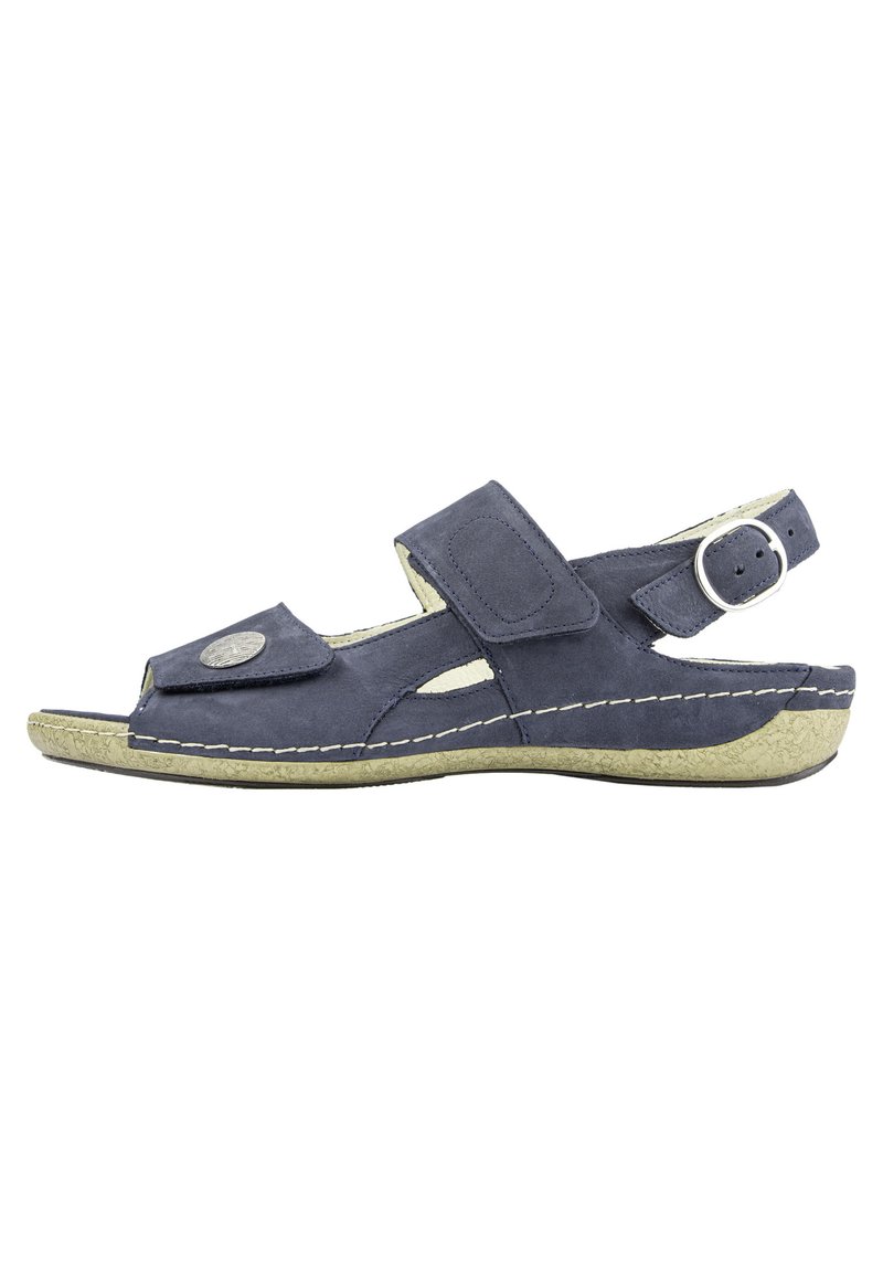 Navy blue suede sandal with an open toe, adjustable strap, decorative metal accent, and a textured light-colored sole.