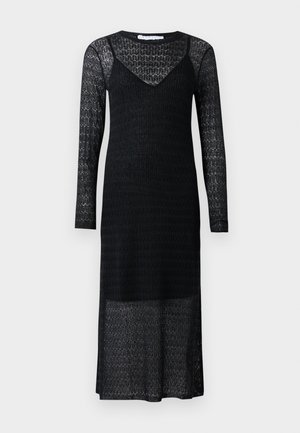Rochie din dantelă neagră, cu mâneci lungi, decolteu în V, cu un model texturat și o tăietură de lungime medie. Dispune de o porțiune inferioară fluidă, ușor transparență.