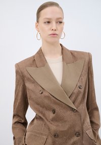 Blazer doppiopetto in tessuto brown texture, con rever a punta in un tono di marrone chiaro a contrasto, due bottoni e tasche laterali.