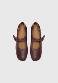 Burgundy leather Mary Jane shoes with a rounded toe, buckle strap, and a smooth texture. Interior is tan with a cushioned insole.