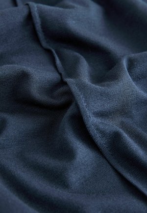 Tissu tricoté bleu foncé avec une texture lisse, présentant des plis et des coutures subtils, mettant en valeur son apparence douce et légère.