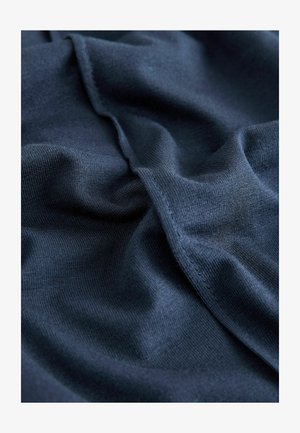 Ciemnoniebieska dzianina z gładką fakturą, z subtelnymi fałdami i szwami, podkreślająca jej miękki i lekki wygląd.