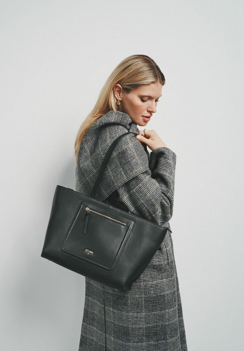 Czarna skórzana torba tote z teksturowanym wykończeniem, z przednią kieszenią na zamek błyskawiczny i długim paskiem. Projekt jest prosty i funkcjonalny.